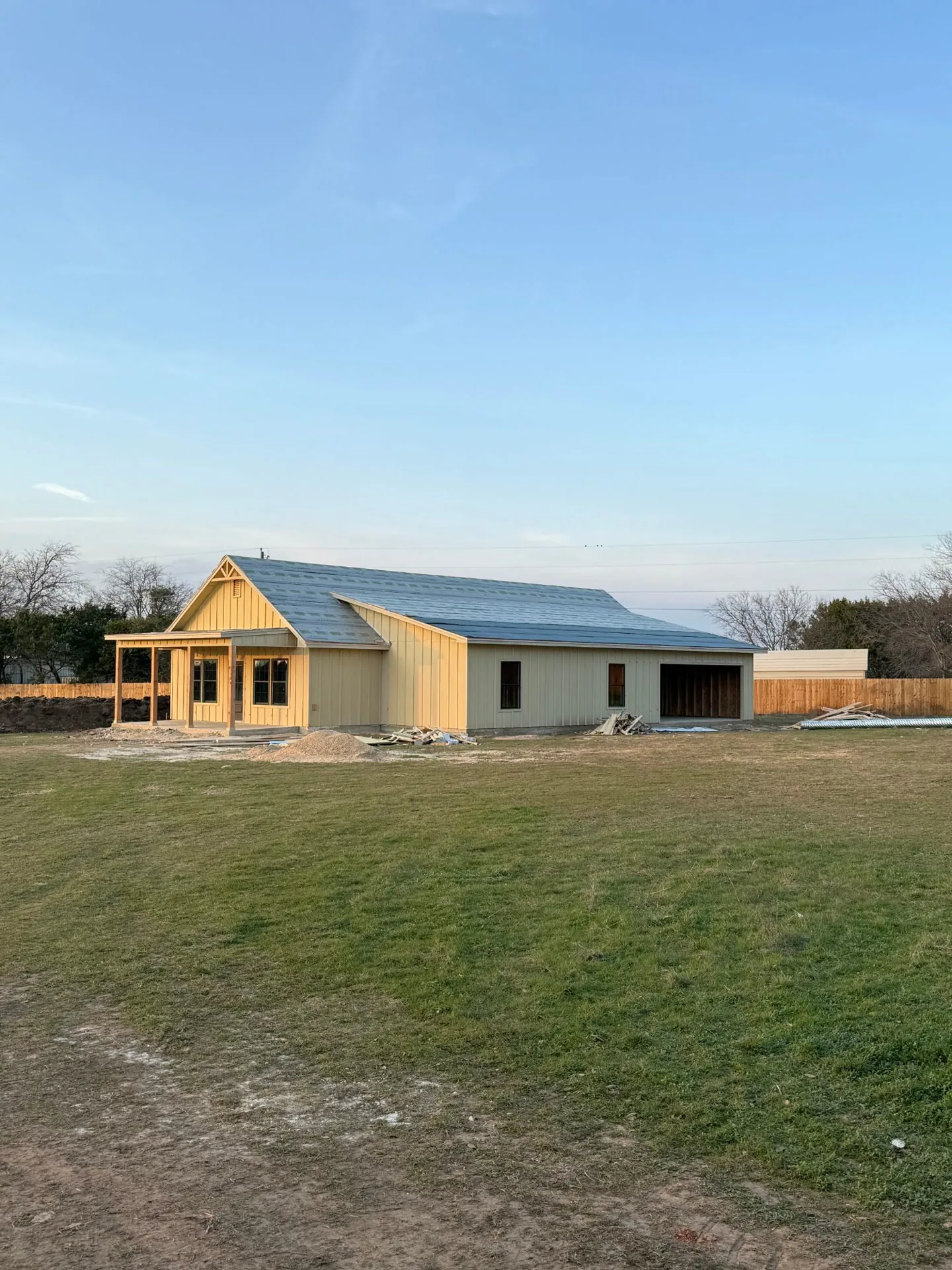 A new farmhouse before painting, with bare tan board-and-batten siding